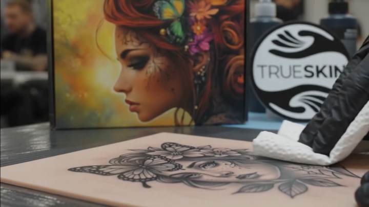 A finished portrait tattooed onto a sheet of TrueSkin, with the TrueSkin banner and packaging artwork behind it.